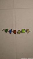 Sterling silver bracelet laid flat showing all six pieces of beach glass in various colors.