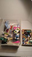 Plastic bin with assorted sewing items including spools of thread, needles, and packages.