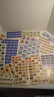 Multiple sheets of unused Canadian stamps spread out, showing a variety of themes and colors.