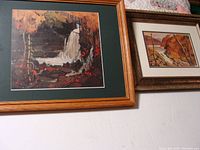 Two framed waterfall prints resting against a wall, showing relief detail and autumn colors in the scenes.