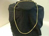 Full view of gold Figaro chain necklace on black display.