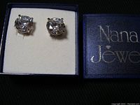Pair of clear, sparkly 10mm cubic zirconia stud earrings in sterling silver prong setting placed in blue Nana Jewel box with cream interior.
