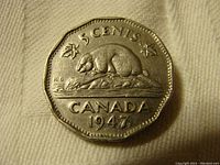 Photo of the coin's reverse side showing a beaver sitting on a rock, the word 'CANADA', the denomination '5 CENTS', and the year '1947' with a dot beneath the date.