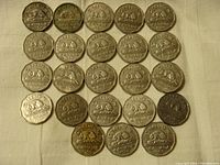 Photo showing 23 circulated Canadian nickels laid flat in a grid pattern on a white cloth, visible beaver design with dates mostly from mid-20th century.