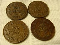 Obverse sides of four Canadian one cent coins dated 1920 (2), 1921, and 1932 showing denomination and maple leaf design.