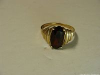 Front angle showing the ring with dark red oval stone set in 10K gold band with stepped shoulder design.