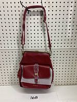 Front view of red Ecosusi small casual backpack purse, showing gold-tone metal frame, kiss-lock closure, front pocket with buckle detail and strap attached.