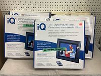 Photo of 2 boxed iQ 12.1 Digital Picture Frames with information on their 12.1 inch LCD display, Twin-Light technology, and digital capabilities.