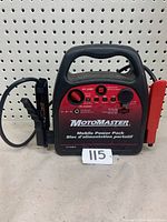 Front view of the MOTOmaster Mobile Power Pack showing brand, model, controls, battery level indicator, output ports, and clamps attached.