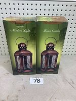 Two original boxed Northern Lights Coachman Lanterns in green packaging on shelf.