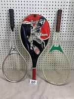 Three racquets shown side by side: Wilson Federer 25 racquetball racquet with cover, Slazenger aluminum tennis racquet, Venture SR mid oversize squash racquet