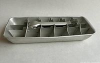Top angle view of vintage aluminum ice cube tray showing all compartments and lever mechanism.
