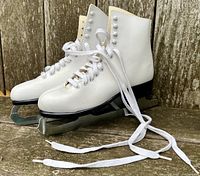 Pair of Bauer white leather figure skates showing side angle with laces undone.