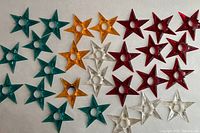 Top view of 27 Glo-Star star-shaped reflectors in four colors (red, green, gold, clear) arranged on a surface, showing size and quantity.