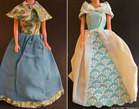 Front view of two Barbie-size ball gowns on dolls, showcasing one blue patterned gown and one blue and white lace gown with pearl accents.