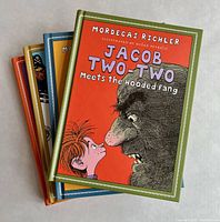 Front view of four hardcover Jacob Two-Two books stacked vertically showing colorful illustrated covers with main character and title text.