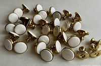 Group photo of 34 white ceramic topped brass knobs and 7 smaller solid brass knobs.