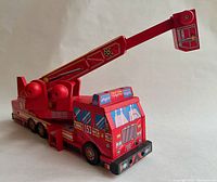 Side angle photo showing full length of fire truck with ladder extended and ruler for scale.