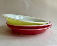 Stacked view of three vintage Pyrex rimmed pie plates showing edge profile and colors: two Flamingo Pink and one Lime Green plate.
