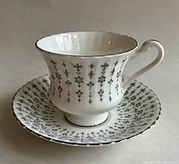 Side view of vintage Royal Standard tea cup and saucer with delicate fleur de lis and floral pattern and platinum trim. Shows the shape, pattern and condition well.