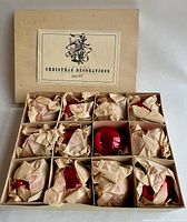 Boxed set of 12 shiny scarlet glass ball Christmas ornaments, each wrapped in tissue paper, contained in a divided cardboard box labeled Christmas Decorations Germany.