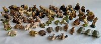 Wide view showing the majority of 68 Wade ceramic animal miniatures arranged on flat surface including many duplicates and variations.