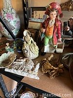 Photo of six vintage statues featuring colonial-style boy and seated woman figurines