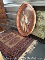 Photo showing part of the Persian prayer rug with fringed edges, wire basket, and two framed vintage pictures (one oval, one rectangular)