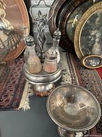 Photo showing vintage swivel stand holding four glass bottles for oil, vinegar, salt, and pepper next to a sterling silver pedestal cup