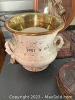 Front and top side view of the ceramic wine bucket showing brass rim and faded 'pour le vin' text.