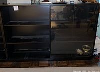 Front view of black wooden bookcase showing adjustable shelves on left and glass doors on right side with shelving inside.