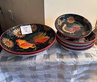 Large and small ceramic bowls with rooster and floral designs shown stacked and side by side