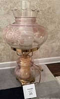 Full view of lamp showing the glass shade and base with pink floral etching and brass base, with power cord visible.