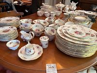 Multiple dinnerware pieces including plates, bowls, cups, saucers, teapot, sugar bowl, creamer and gravy boat arranged on table