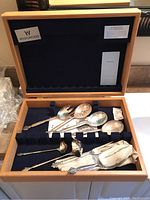 Open Wedgwood wooden box showing four serving spoons and anti-tarnish cloth