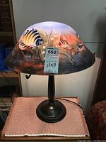 Front and side view of one lamp showing the painted fish design on the glass shade and metal base.