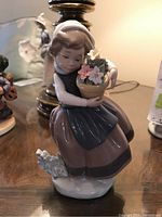 Front view of the Lladro porcelain figurine showing the girl sitting with flower pot in hands and small dog at her feet.