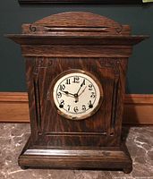 Full front view of oak-cased mantle clock showing case profile, dial and carved scroll details