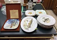 Photo showing the Royal Doulton Christmas in Norway collector plate in its box alongside the Eschenbach fish plates and platter and Johnson Bros fruit plates.