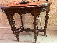 Front view of intricately carved wood side table showing carved legs and apron.