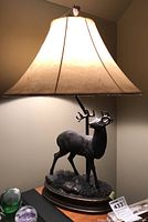 Side view of lamp illuminated, showing deer statue base and tapered shade