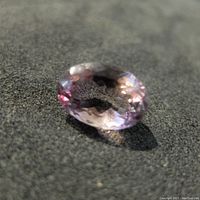 Close-up photo of the oval cut ametrine gemstone showing its purple and yellow bi-color hues and surface detail.