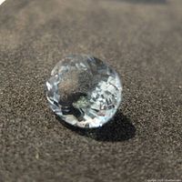 Close-up of light blue oval faceted blue topaz gemstone on dark fabric background