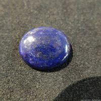 Top view of the oval lapis lazuli gemstone showing deep blue color and some surface reflections.