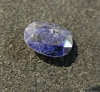 Close-up of the oval cut blue sapphire gemstone showing color and surface details.