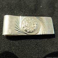 Front view of Mexican silver money clip showing engraved Aztec calendar design and decorative lines on polished silver surface.