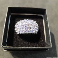 Top angled close-up view of sterling silver ring featuring multiple small tanzanite stones in three rows inside black box.