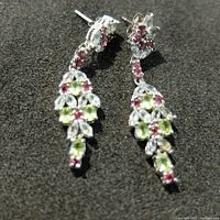 Front view of sterling silver earrings showing topaz, garnet, and peridot stones in intricate floral and leaf design on black background.