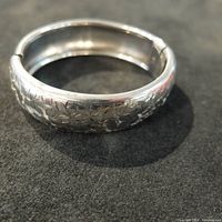 Close-up image of the vintage sterling silver bangle showing floral engravings on the surface.