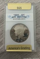 Front side of 1989S Kennedy Half Dollar graded PR70CAM by SGS showing obverse portrait and grading label.